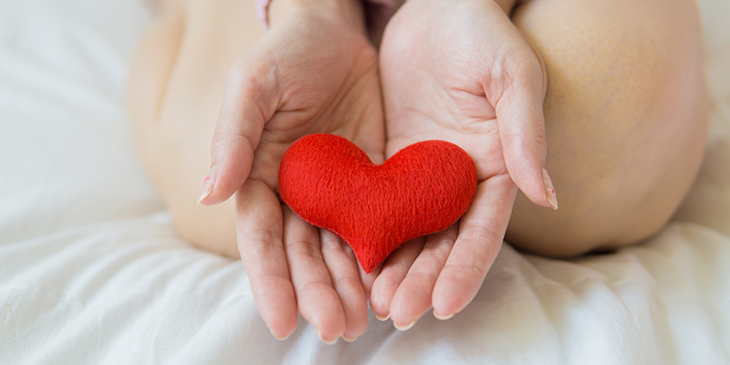 A woman holding a fabric heart in her open hands