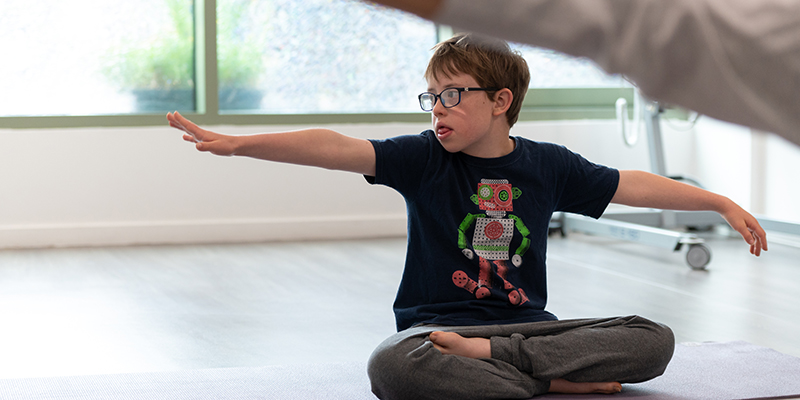 A young boy sitting on the floor with his arms outstretched