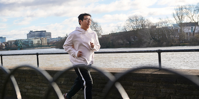 A man running outside next to a river