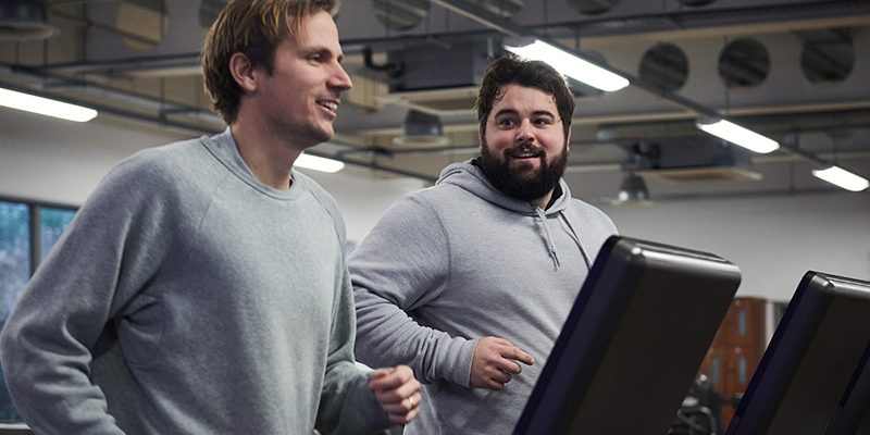 Two men running next to each other on treadmills in a gym