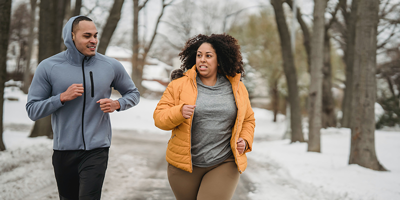 A man and a woman jogging in snowy conditions
