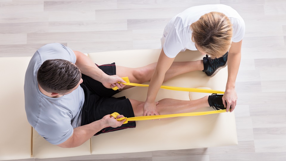 A physiotherapist giving resistance band exercise treatment to a patient