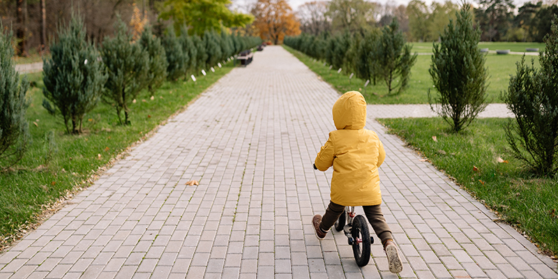 A young child riding a balance bike in a quiet park