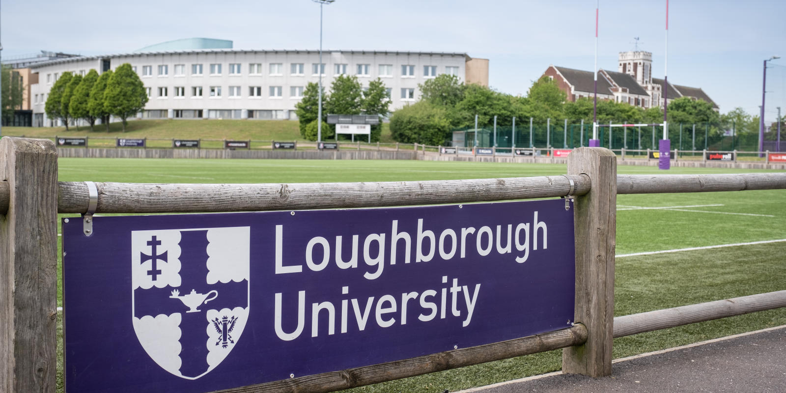 A Loughborough University sign in front of a rugby pitch