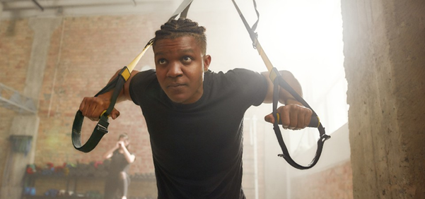 A young man exercising with suspension straps in a gym