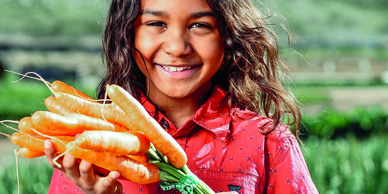 A young girl holding a bunch of carrots