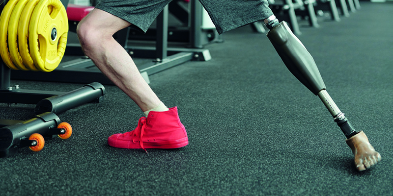 An amputee wearing a prosthetic leg and working out in a gym