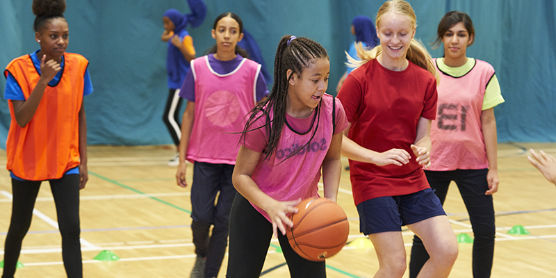 Teenage girls playing basketball in a sports hall