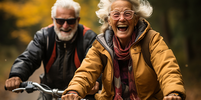 Cheerful active senior couple with bicycle in public park together