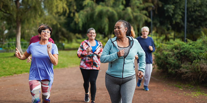 Group of multiracial senior friends running at city park