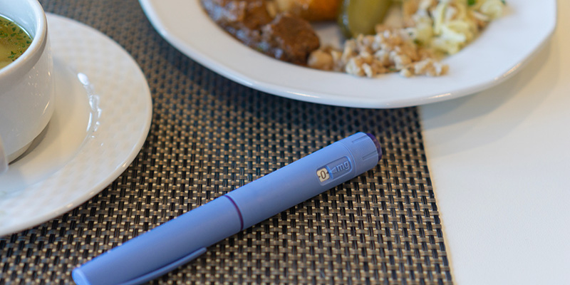 A medical syringe alongside a healthy plate of food
